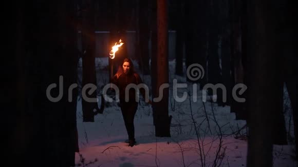 一个年轻的被吓坏了的女人手里拿着火炬在夜间的冬林里躲避危险视频的预览图