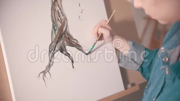 一位留着短发的年轻女子在一棵颜色更深的树干上作画视频的预览图