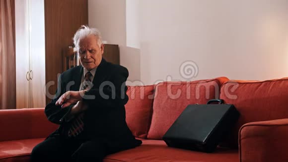 老爷爷老爷爷正拿着一个手提箱坐在沙发上在样本上检查时间视频的预览图