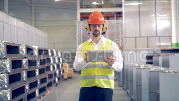 一名男子在工业设施工作检查他的平板电脑上的信息视频的预览图
