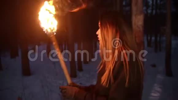 一个年轻的被吓坏了的女人手里拿着火炬在森林里躲避危险视频的预览图