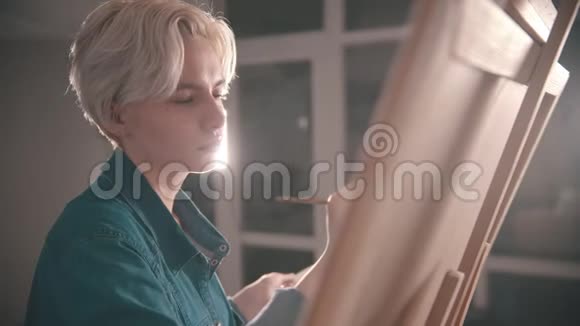 一位年轻的金发美女画家在画室里画画视频的预览图