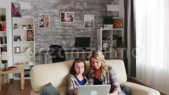 年轻的母亲在女儿的教育中使用笔记本电脑视频的预览图
