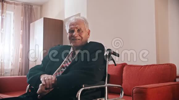 年迈的祖父微笑的祖父坐在轮椅上看着摄像机视频的预览图