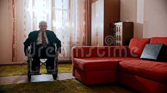 年迈的祖父快乐的祖父正坐着轮椅在房间里转悠视频的预览图