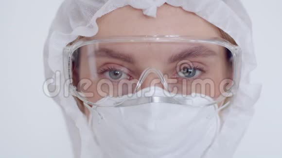 用呼吸器安全眼镜和化学防护服近距离观察女孩的眼睛一位年轻的女医生看着视频的预览图