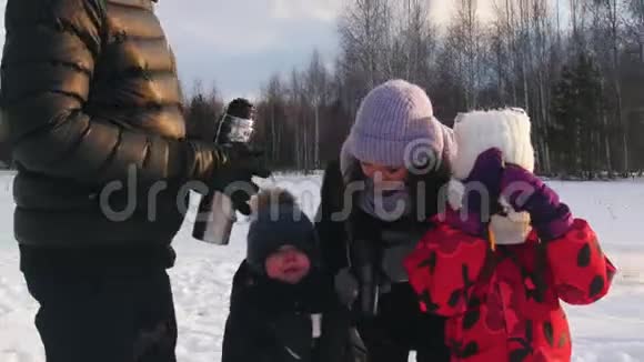 快乐的一家人在冬季森林附近的户外喝热饮料视频的预览图