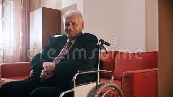 年迈的祖父快乐的祖父坐在轮椅上看着摄像机视频的预览图