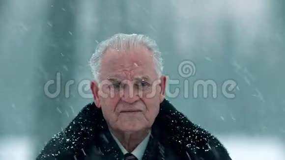 年迈的祖父白发苍苍的悲伤的祖父站在外面下雪视频的预览图