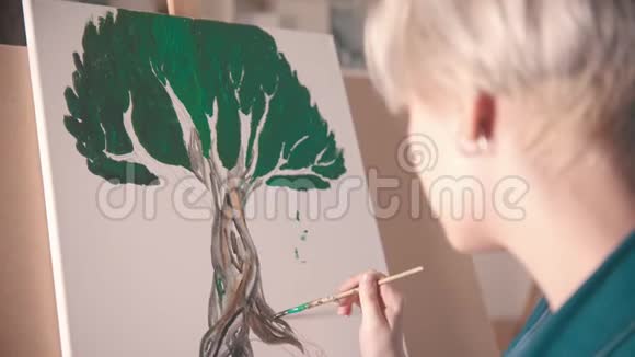 一位年轻的金发女画家用深色画树干视频的预览图