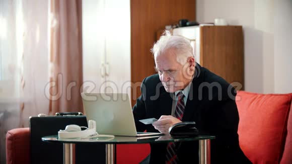 老爷爷老爷爷在房间里把银行卡号输入笔记本电脑视频的预览图