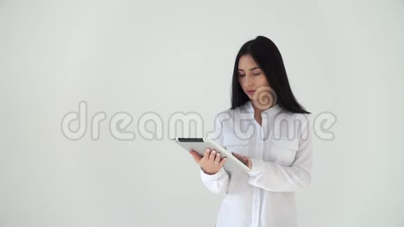 一个女孩用白色背景的数字平板电脑读新闻一位年轻女子正在用电脑看新闻视频的预览图
