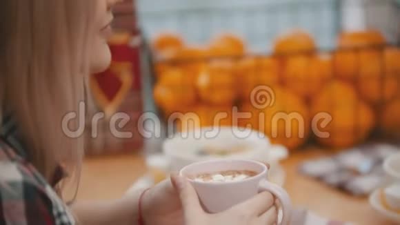 一个头发很浅的年轻女人喝着棉花糖的咖啡视频的预览图