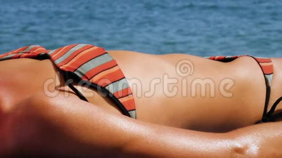 性感的女人在海滩上晒日光浴视频的预览图