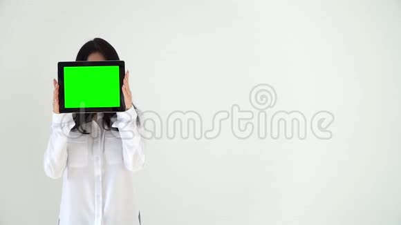 一个十几岁的女孩拿着一个数码平板电脑脸前有一个色度一个穿白色上衣的女孩视频的预览图
