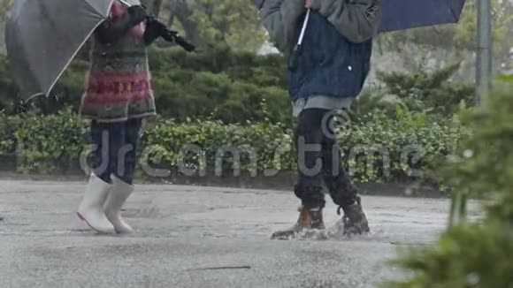 男孩和女孩带着雨伞在倾盆大雨中缓慢地跳跃视频的预览图