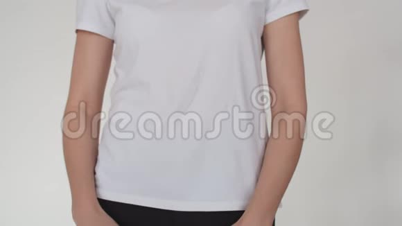 一个女人的腹部的特写一个女人把她的手并挤压它一个穿白色t恤穿白色的年轻女人视频的预览图