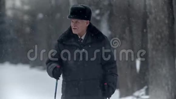 老爷爷体贴的爷爷正在冬季公园里的北欧漫步视频的预览图