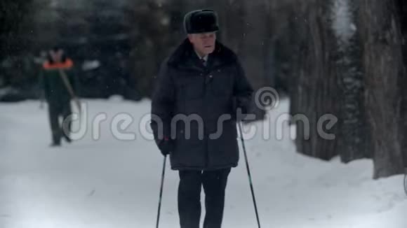一位年迈的祖父祖父正在一个冬季公园里散步四处张望视频的预览图