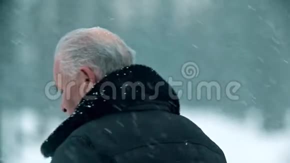 一位年迈的祖父头发灰白头秃的祖父正站在外面下雪视频的预览图