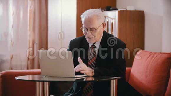年迈的祖父戴眼镜的老祖父正在电脑上打字视频的预览图