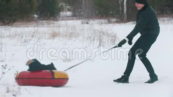 一个男人把孩子卷在充气雪橇上视频的预览图