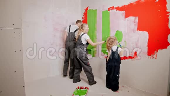 一家人用滚筒作画用绿色油漆刷白墙壁视频的预览图