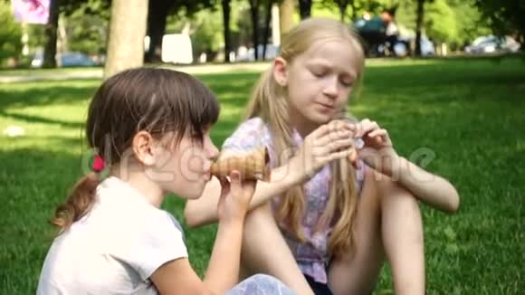 坐在绿色草坪上吃冰淇淋的小女孩视频的预览图