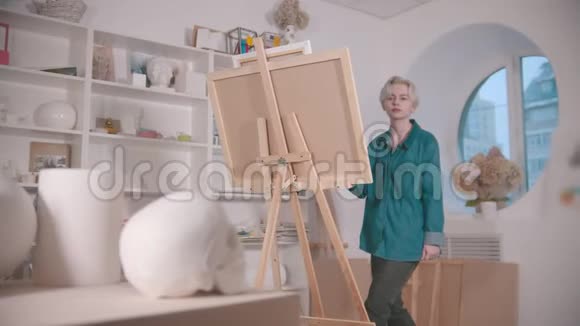 一位年轻迷人的女艺术家从桌子上画一个头骨和其他图形视频的预览图