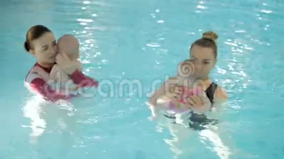 游泳课在游泳池里教婴儿游泳的母亲视频的预览图