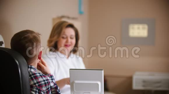 眼科诊所的一种治疗方法女医生坐在桌子旁一个小男孩看着墙上的投影视频的预览图