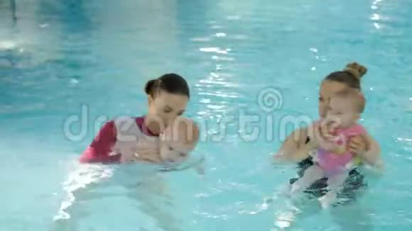 游泳课在游泳池里教婴儿游泳的母亲视频的预览图