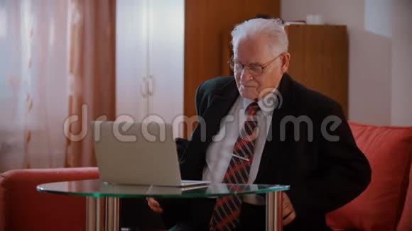 一位年迈的祖父在家正试图处理一台电脑视频的预览图