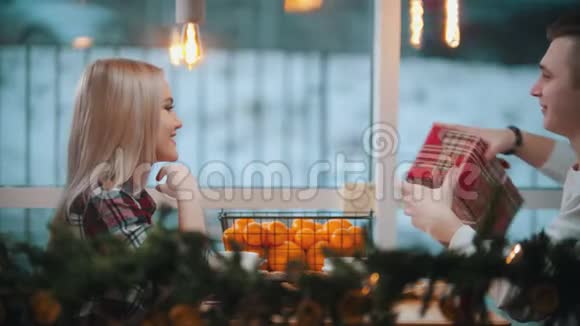 一对夫妇在咖啡馆里一个男人给他的女朋友一份圣诞礼物视频的预览图