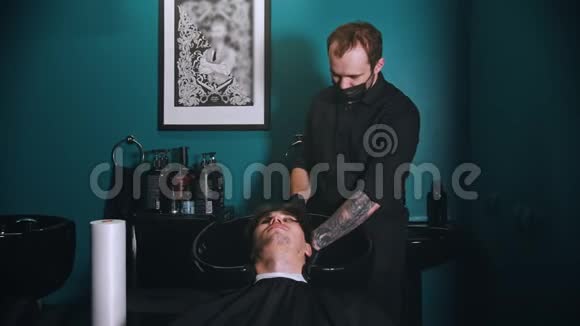理发店的理发师戴着黑色面具给他的客户洗头视频的预览图