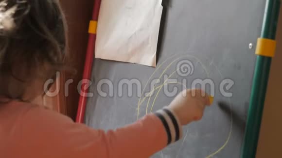 可爱的小女孩在粉笔板上用蜡笔画视频的预览图