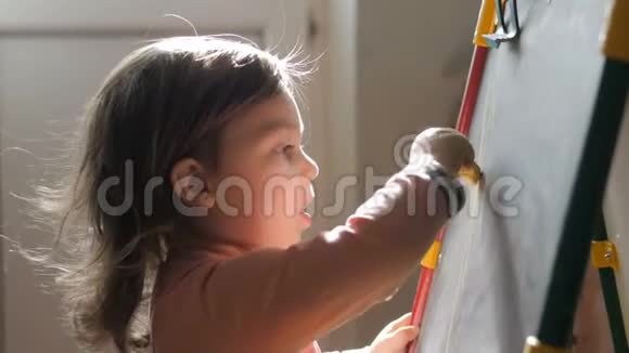 可爱的小女孩在粉笔板上用蜡笔画视频的预览图