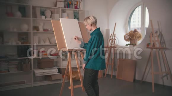 一位年轻的金发女艺术家用铅笔在画布上画素描视频的预览图
