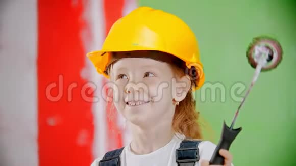 戴着头盔的快乐小女孩正拿着油漆滚筒看着摄像机视频的预览图