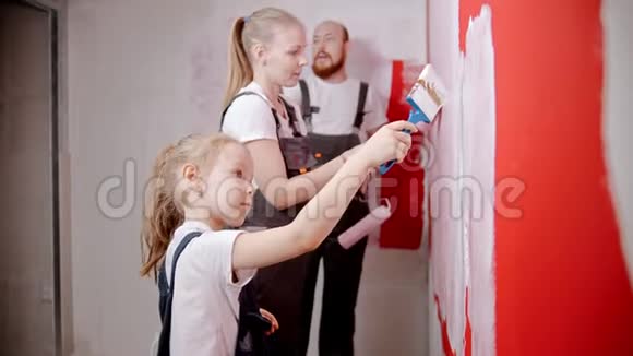 美丽的小女孩正在和她的父母一起粉刷墙壁视频的预览图