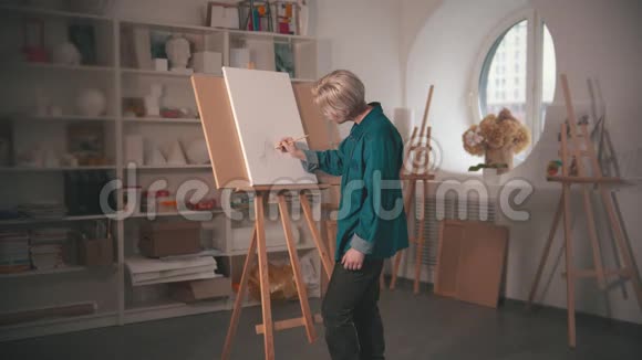 一位年轻的金发女艺术家在画布上画素描看着它视频的预览图