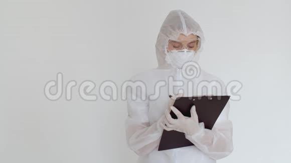 一个化学防护的女孩在一张纸上记录数据然后看着相机一个穿白色一次性衣服的女孩视频的预览图