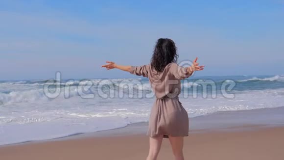 女人在沙滩上双臂向上行走夏季旅行理念视频的预览图