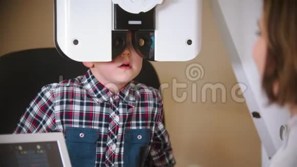 眼科诊所的一种治疗方法用镜片透过大型特殊装置检查小男孩视力视频的预览图