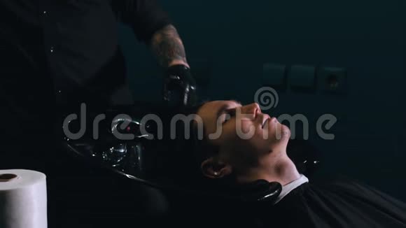 一个戴着黑色面具的理发师给客户洗头视频的预览图