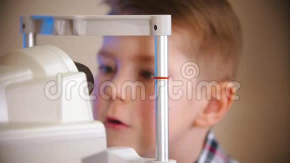 一个在眼科诊所接受治疗的男孩那个男孩在检查设备的镜头视频的预览图