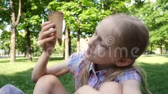 坐在绿色草坪上吃冰淇淋的小女孩视频的预览图