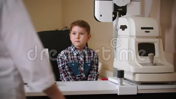 眼科诊所的治疗成熟的女医生坐在男孩面前视频的预览图