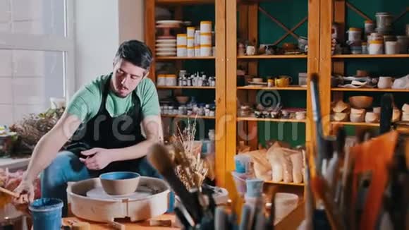 一个在制陶车间工作的男陶工用蓝色画锅视频的预览图