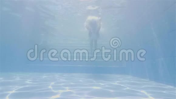 在度假酒店的游泳池里游泳时微笑的男人竖起大拇指面对快乐的人在蓝色的水里游泳视频的预览图